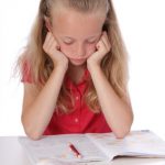 fillette de 9 ans faisant ses devoirs, ennuyée